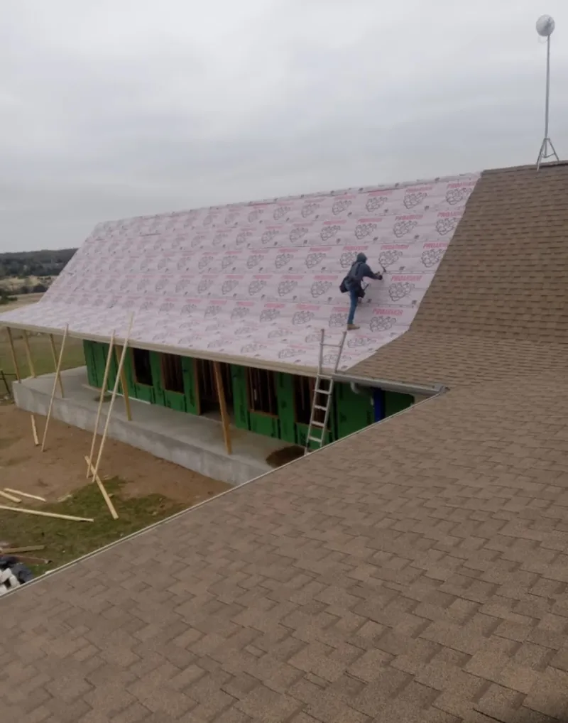 Worker preparing underlayment for a metal roof installation in San Francisco
